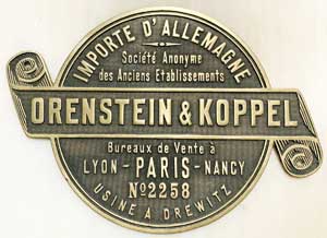 Fabrikschild Orenstein&Koppel, Drewitz: Fabriknummer: 2258, Baujahr: 1907. Messingguss, rund, Riffelgrund mit Rand. D = 210 mm, Schleife = 305 mm. Das Schild ist von einer Lok fr A.Petit Serailler Eugen, fr Algerien. (Ct-1000mm)