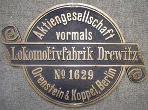 Orenstein&Koppel 1629, Drewitz, Messingguss, Riffelgrund mit Rand, rund, von Baulok der Firma Holzmann