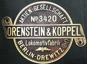 Fabrikschild Orenstein&Koppel, Berlin-Drewitz (Bhf.), Fabriknummer: 3420, Baujahr: 1909. Messingguss rund mit Schleife, Riffelgrund mit Rand.D = 265 mm. Das Schild ist von einer Bt, Spurweite 1435mm. Ein sehr sch�nes Schild, ohne "ehemals" und ohne seitliche Verzierungen.