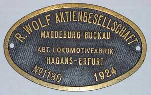 Fabrikschild Wolf Aktiengesellschaft, Abteilung Lokomotivfabrik HAGGANS, Erfurt. Messingguss oval, Riffelgrund mit Rand (GMsmR). Das Schild ist von der DRG 93 1180