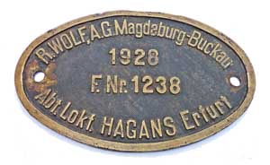 Fabrikschild R. Wolf, A.G. Magdeburg-Buckau,  Abt.  Lokfabrik  Hagans Erfurt. Fabriknummer: 1238, Baujahr: 1928, Messingguss, oval, Riffelgrund mit Rand. Das Schild ist von der DRG 64 082.