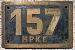 Hildesheim Peiner Kreiseisenbahn HPKE. 1929 - 1949 Braunschweig-Schöninger Eisenbahn, dort Betriebsnummer 153. 1949 - 1965 im Besitz der HPKE. 1964 in Hildesheim-Nord abgestellt. 1965 ausgemustert und verschrottet. Eine ELNA 5 Maschine. Umgebautes Messinggussschild: Vorher 153 B.S.E. Ziffer 3 und Buchstaben abgeschliffen und durch eine geschraubte Ms Ziffer 7 und genietete Ms Buchstaben ersetzt. BxH = 381 x 250 mm.